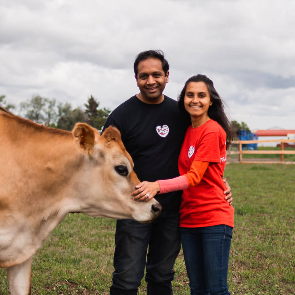 Founders, Shaleen and Shilpi Shahs standing next to a rescued cow.